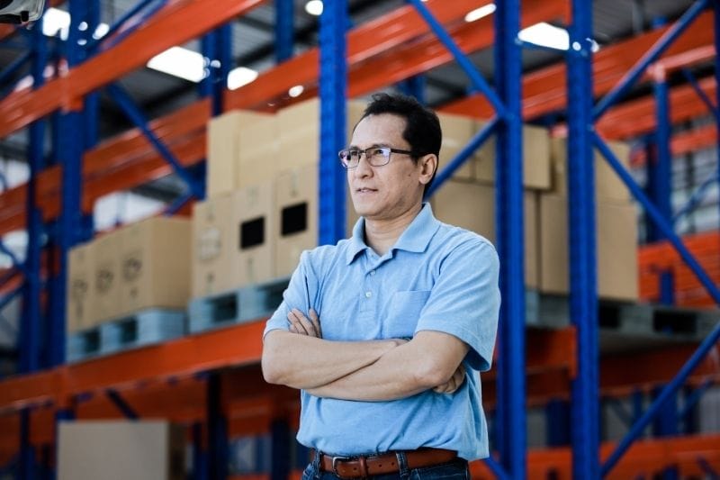 Singapore small business owner standing inside a warehouse with inventory shelves