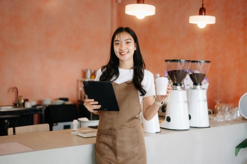 Singapore cafe owner managing customer orders and business leads on a tablet